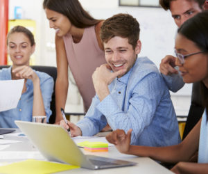 Colleagues working together in a busy office, close up